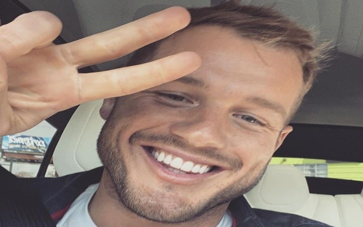 Colton Underwood showing his two fingers and posing happily.